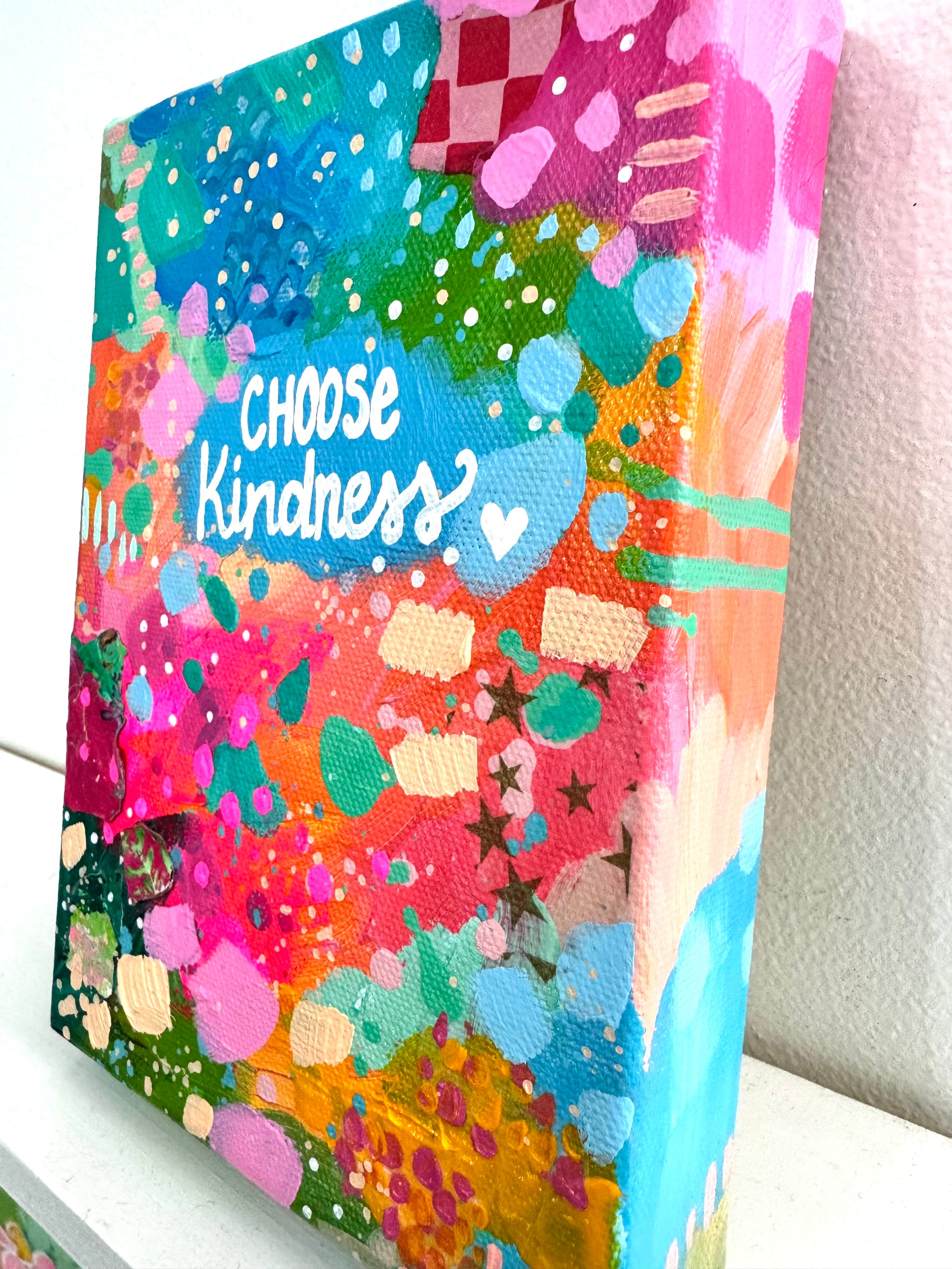 Abstract colorful canvas with the words choose kindness painted on. This image is a side view of the painting 