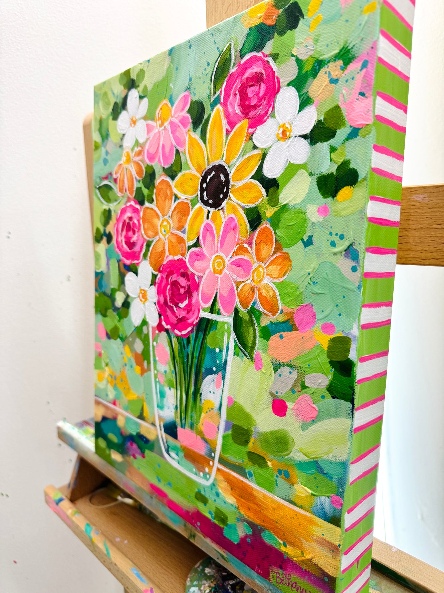 Colorful floral painting on a canvas sitting on a wooden easel.