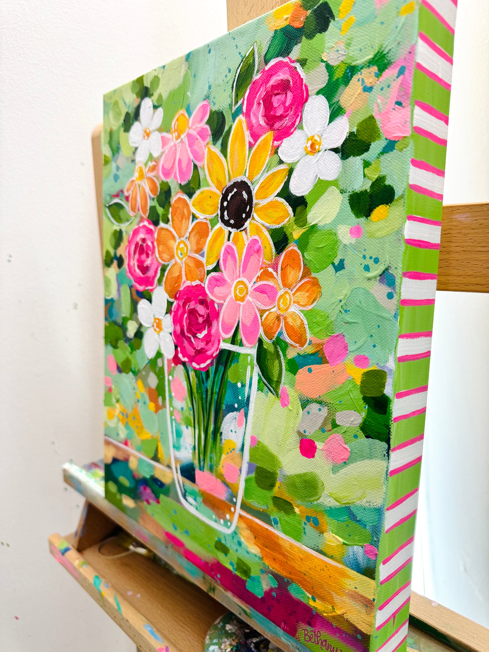 Colorful floral painting on a canvas sitting on a wooden easel.