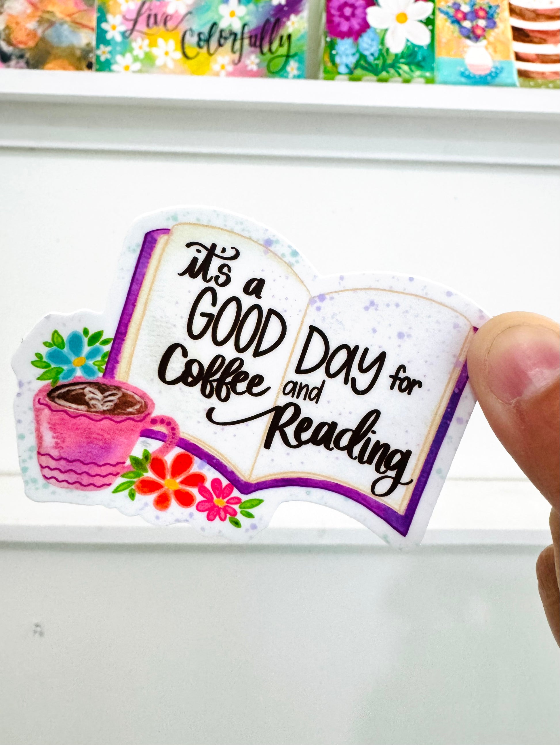 Sticker with 'It's a Good Day for Coffee and Reading' text held by a hand.