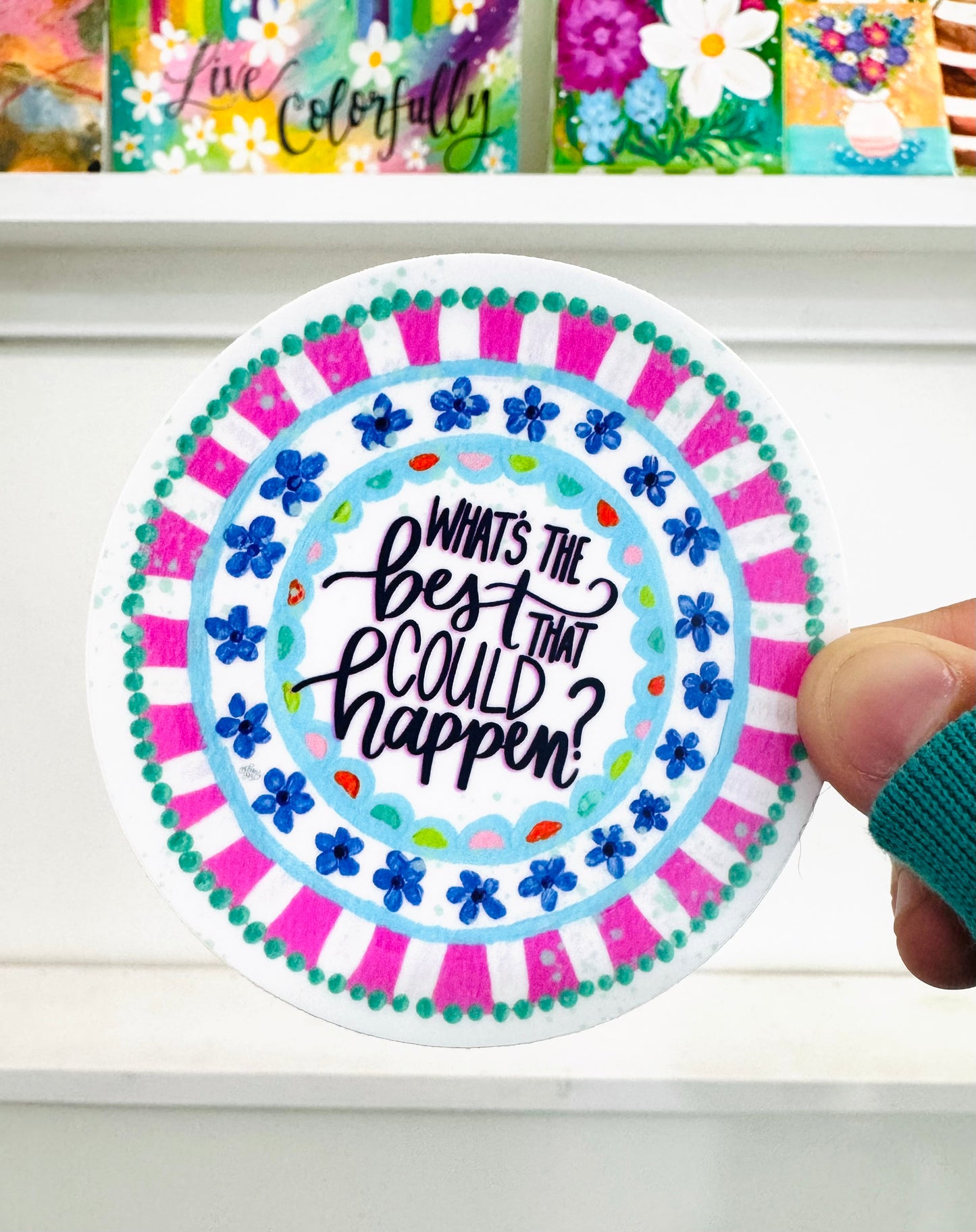 Circular sticker with motivational text held by a hand against a white background