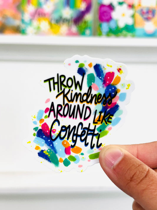 Sticker with 'Throw Kindness Around Like Confetti' text held by a hand against a colorful background.