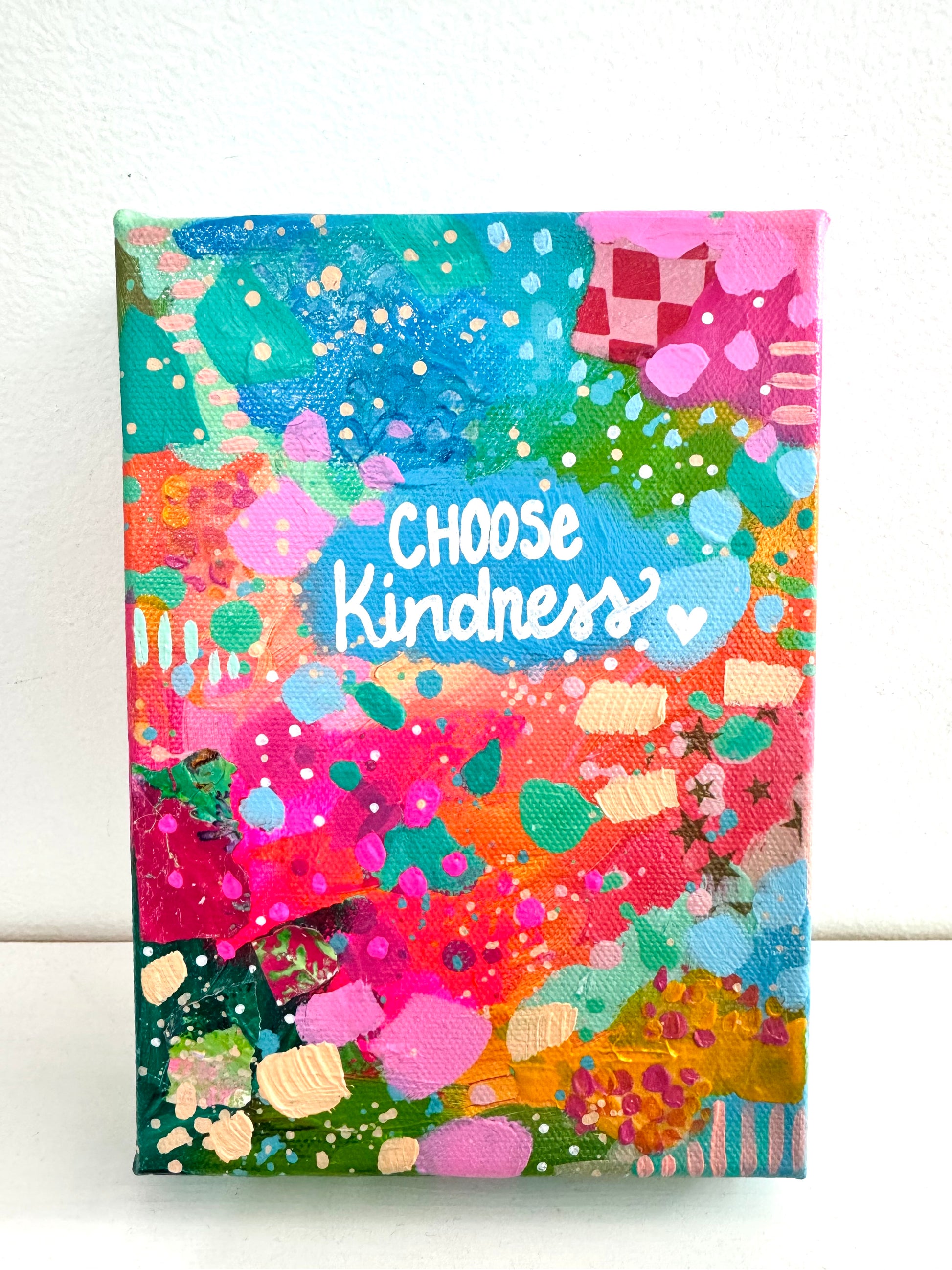 Abstract colorful canvas with the words choose kindness painted on 